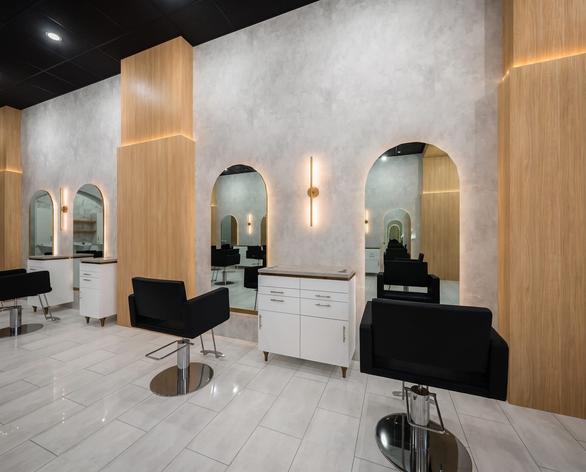 Styling stations with arched mirrors and warm sconce lighting